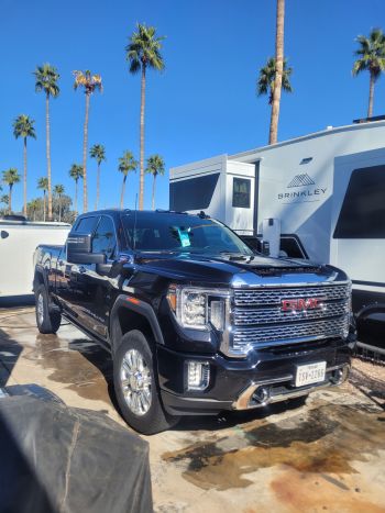 Black GMC pickup truck parked beside an RV in a palm-lined campsite after detailing